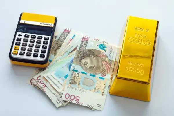 Kalkulator, polskie banknoty 500 zł i sztabka złota 1000g. Zastanawiasz się, ile kosztuje 1 uncja złota?