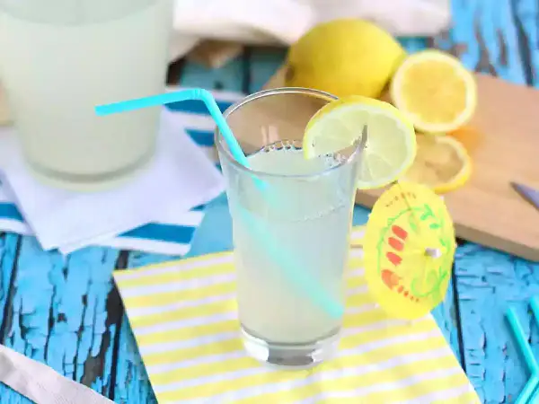 Ett glas hemgjord lemonad med citronskiva och sugrör. Perfekt för ett enkelt lemonad recept en varm sommardag.