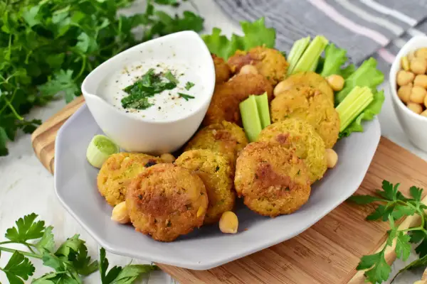 Chrupiące falafelki z ciecierzycy, podane z sosem jogurtowym i warzywami. Idealny falafel przepis na przekąskę.