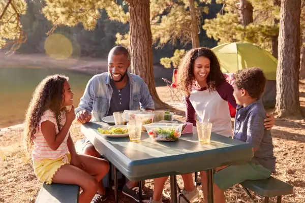 Familia disfrutando un picnic junto a un lago, una escena perfecta de qué hacer en familia al aire libre.