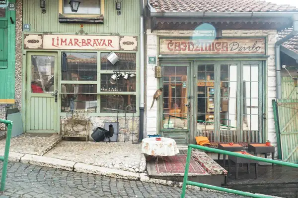 Faszinierende Szene in der Sarajevo Altstadt: Ein Vogel sitzt auf einem Geschäftsschild, davor ein Tisch mit Blumen.