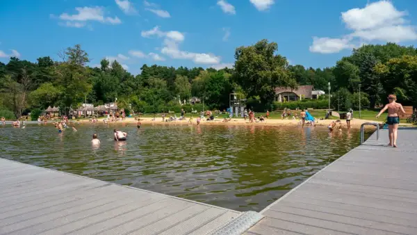 Słoneczny dzień na kąpieliskach w Poznaniu. Ludzie kąpią się, opalają na plaży i odpoczywają nad wodą.