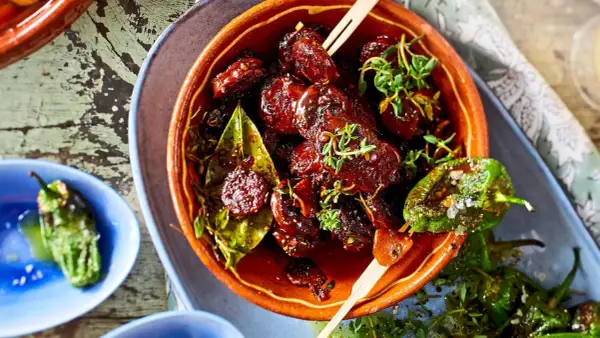 Leckeres Tapas Fingerfood: Glasierte Datteln mit Kräutern und geröstete Pimientos de Padrón.