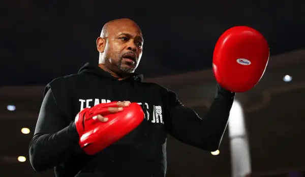 Roy Jones Jr. sweats during training, preparing for one of his best fights. He holds red boxing pads, ready to train.
