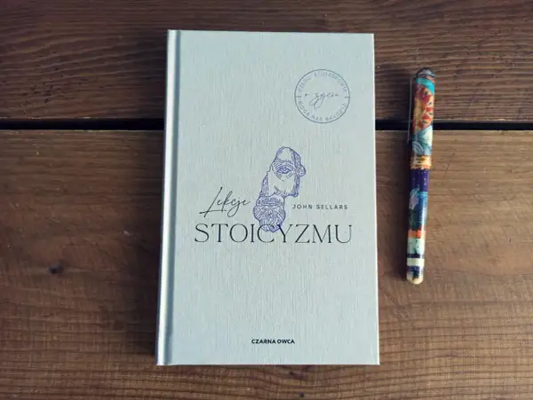 Książka "Lekcje stoicyzmu" Johna Sellarsa obok ozdobnego pióra. Inspiracja dla tych, którzy szukają mądrości w literaturze.