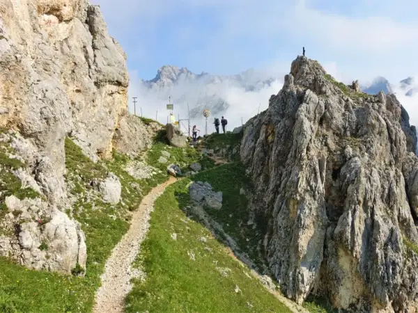 Wanderer auf der Gatterl Tour zur Zugspitze genießen den Ausblick auf felsige Gipfel und Wolkenmeere.