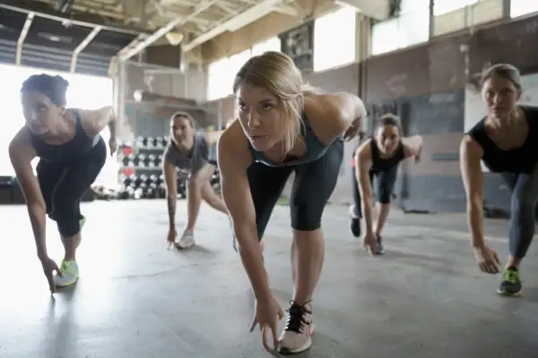 Donne in posizione di partenza per un allenamento intensivo. Questo è un esempio di cosa è un bootcamp: disciplina e fatica per raggiungere la forma fisica.
