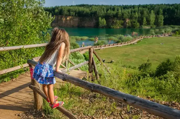 Dziewczynka na drewnianym pomoście podziwia Park Gródek Jaworzno. Cena wstępu jest niska, a widoki zachwycają.