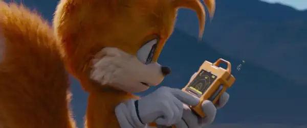 Tails Sonic, z dwoma ogonami, analizuje dane na żółtym urządzeniu.