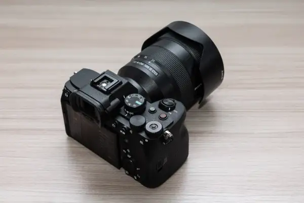 Aparat Sony a7v z obiektywem 24-105 mm G OSS na drewnianym blacie.