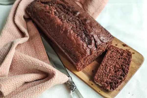 Un délicieux gâteau yaourt chocolat, moelleux et intense, prêt à être dégusté. Une tranche coupée révèle sa texture aérée.