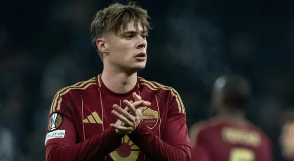 Piłkarz Nicola Zalewski w bordowej koszulce AS Roma z żółtymi pasami na ramionach.