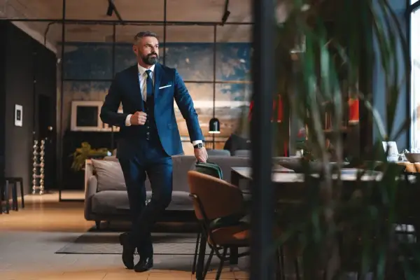 Ein Mann im eleganten dunkelblauen Lounge Suit steht lässig in einem stilvollen Loft.