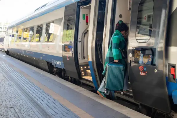 Kobieta z walizką wsiada do pociągu Pendolino. Szybkość i komfort podróży to jego znaki rozpoznawcze.