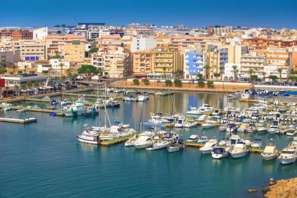 Puerto deportivo con muchos barcos y edificios de colores. Descubre qué hacer en Roquetas de Mar.