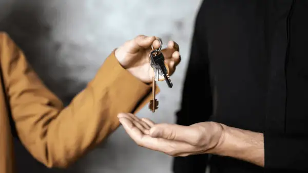 Mani che si scambiano chiavi, simbolo di un immobile in comproprietà abitato da un solo proprietario.