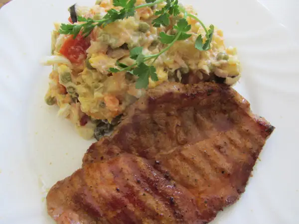 Ein saftiges Schweinefilet mit einem bunten spanischen Salat, garniert mit Petersilie.