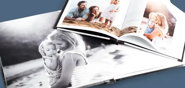 Otwarta fotoksiążka i fotoalbum prezentują rodzinne chwile: mama z dzieckiem na czarno-białym zdjęciu i rodzice z córką na plaży.