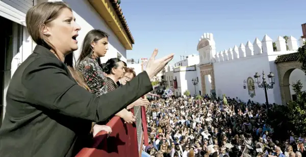 Mujeres en un balcón observan una multitud y escuchan saetas populares.