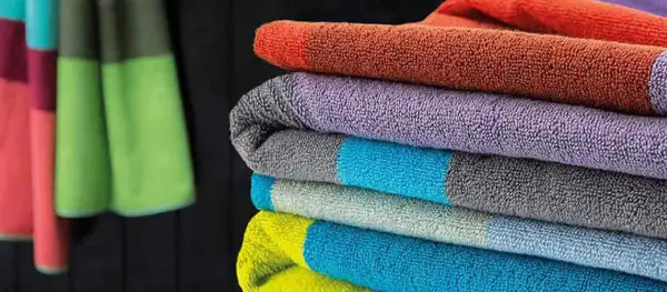 Bunte bad textilien, gestapelt und hängend, schaffen eine fröhliche Atmosphäre im Badezimmer.