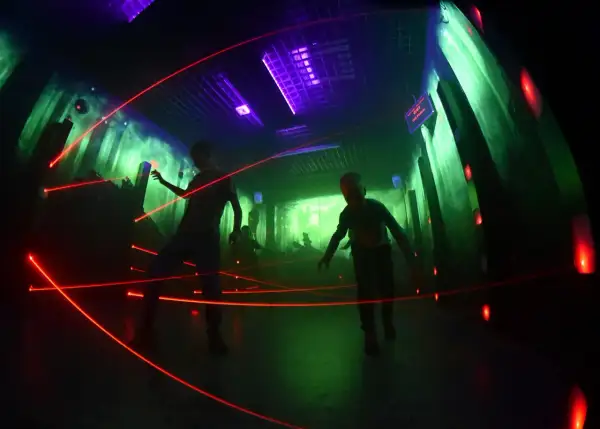 Dzieci bawią się w laserowym labiryncie w Krakowie, unikając czerwonych promieni.