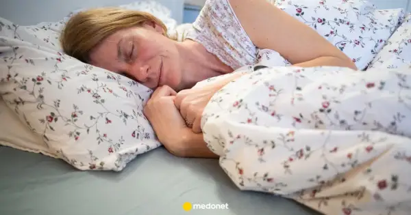Kobieta zasypia w łóżku, otulona pościelą w kwiaty. To idealny moment na czytanie przed snem.