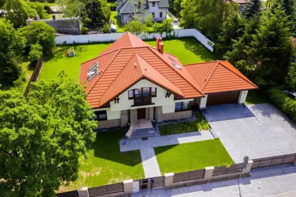 Piękny dom z czerwonym dachem i ogrodem. Zastanawiasz się, ile kosztuje projekt domu?