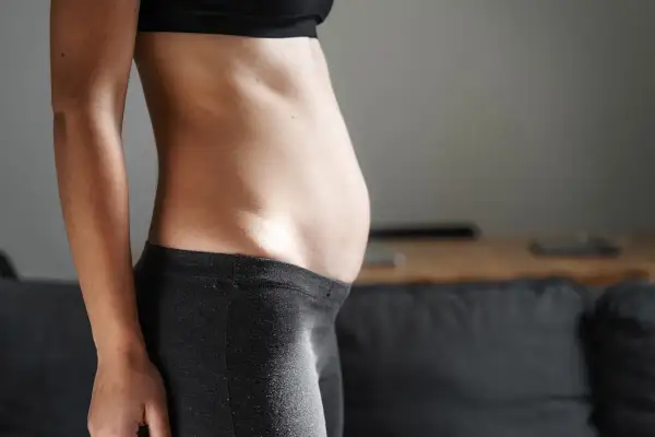 Profilo di una donna con addome prominente, possibile segno di diastasi addominale.