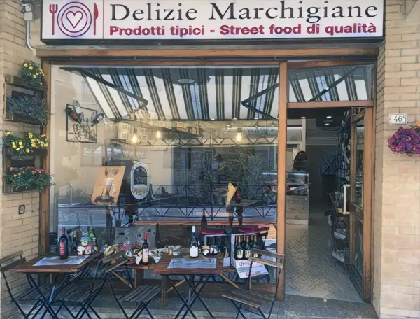 Delizie Marchigiane: prodotti tipici e street food di qualità ad Ancona. Tavolini all'esterno invitano a gustare le specialità locali.