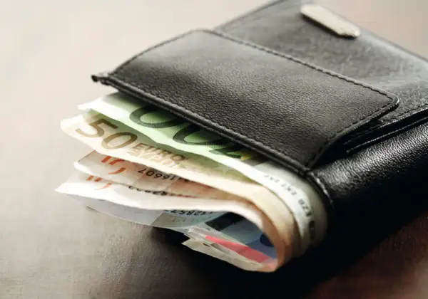 Schwarzes Lederportemonnaie mit Euro-Scheinen. Die Scheine deuten auf die Gehaltszahlung nach dem tarifvertrag wohnungswirtschaft eingruppierung hin.