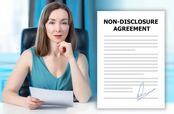 Kobieta z dokumentem w ręku obok umowy o poufności (NDA). Co to jest NDA? To umowa o zachowaniu poufności.