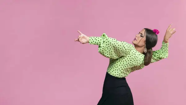 Mujer con blusa verde de lunares y falda negra, lista para bailar sevillanas con gracia y pasión.