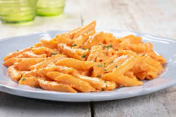 Penne cremose con salsa rosa, un'idea per primi piatti sfiziosi. Spolverata di parmigiano e prezzemolo fresco.