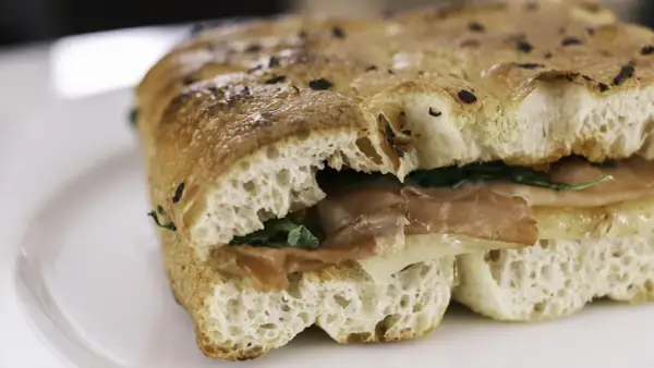 Un sandwich gourmand garni de jambon et de fromage, servi dans un pain italien moelleux et croustillant.