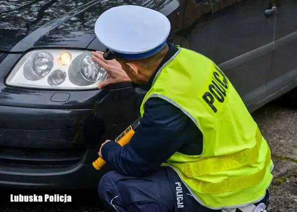 Policjant sprawdza reflektor, czy żarówki postojowe led są legalne. Lubuska Policja.