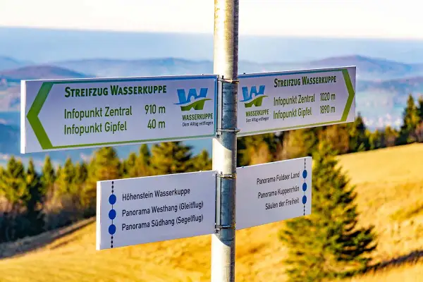 Wegweiser am Gipfel der Wasserkuppe für Wanderer. Hier beginnt der Streifzug Wasserkuppe, mit Zielen wie Infopunkt Zentral und Gipfel.