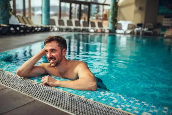 Uśmiechnięty mężczyzna relaksuje się w basenie. Idealne miejsce na odpoczynek i regenerację – takie jak termy Opole.