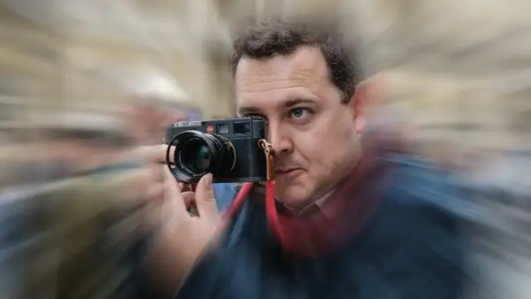 Man with Leica camera, possibly contemplating the best focal length for street photography.