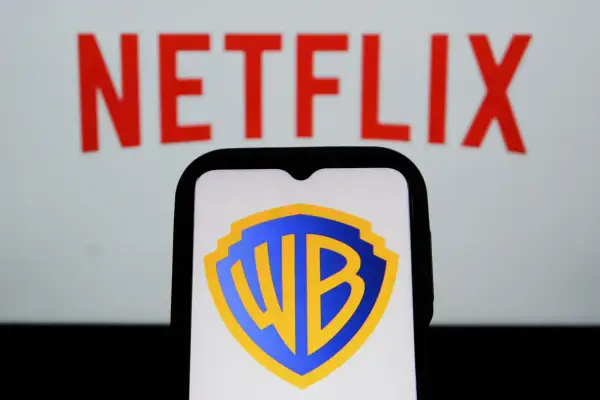 Logo Warner Bros. na ekranie telefonu, w tle napis Netflix. Analiza akcji WBD.