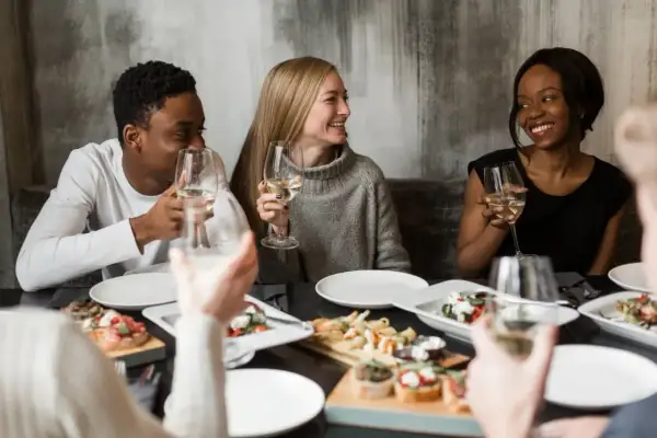 Vänner njuter av middag och vin. Perfekt för att ställa 100 roliga frågor och lära känna varandra bättre.