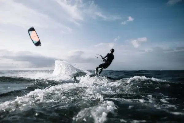Kitesurfer w akcji, pokonujący fale. Dynamiczne sporty wodne w pełnym blasku.