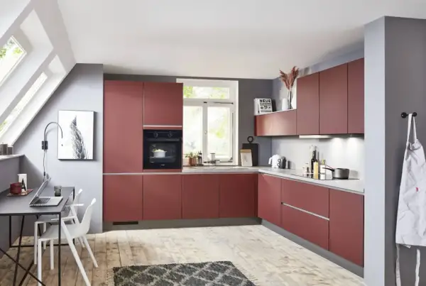 Cocina moderna y alargada con gabinetes rojos, encimeras grises y suelo de madera. Perfecta para distribuir tu espacio.