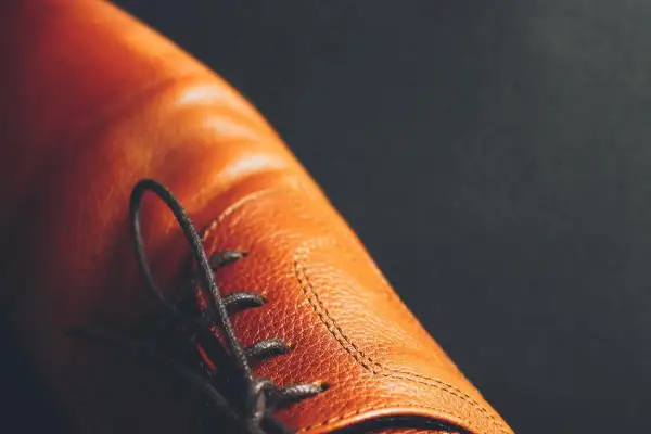 Gros plan sur une chaussure en cuir marron, avec ses lacets noirs. Une question se pose : peut on teindre des chaussures en cuir pour changer leur couleur ?