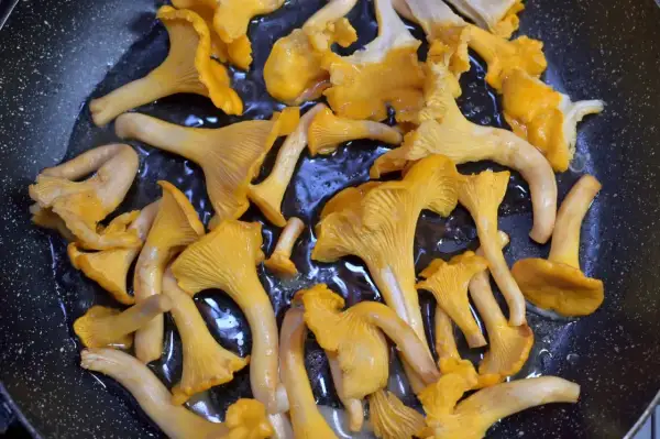 Setas de rebozuelo doradas y jugosas se cocinan en una sartén, listas para ser parte de un delicioso plato, como un champignon de Paris.