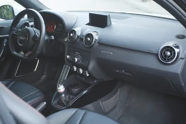 Vue de l'intérieur d'une Audi A1, avec le volant, la console centrale et les sièges en cuir noir.