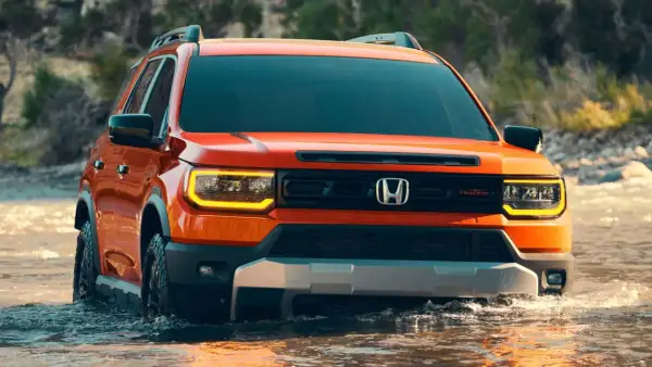 Pomarańczowy Honda Passport TrailSport pokonuje wodę, gotowy na przygodę.