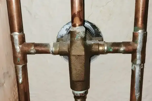 Plomberie en cuivre avec dépôts verts, signe des inconvénients de l'eau trop douce qui corrode le métal.