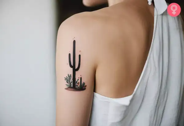 Delikatny kaktus tatuaz na ramieniu, otoczony pustynnymi roślinkami.