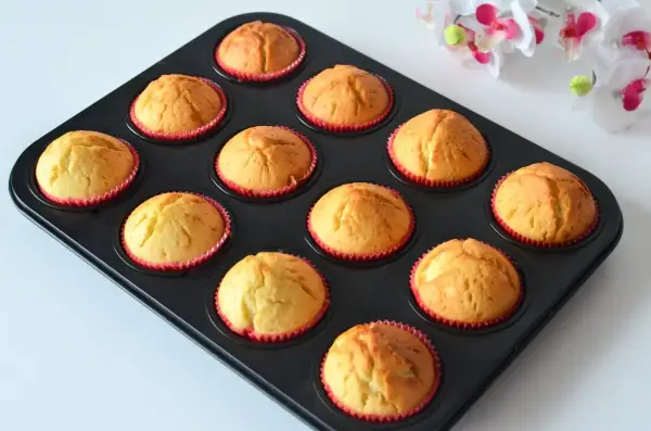 Upieczone, wilgotne muffinki jogurtowe w czerwonych papilotkach, gotowe do jedzenia.