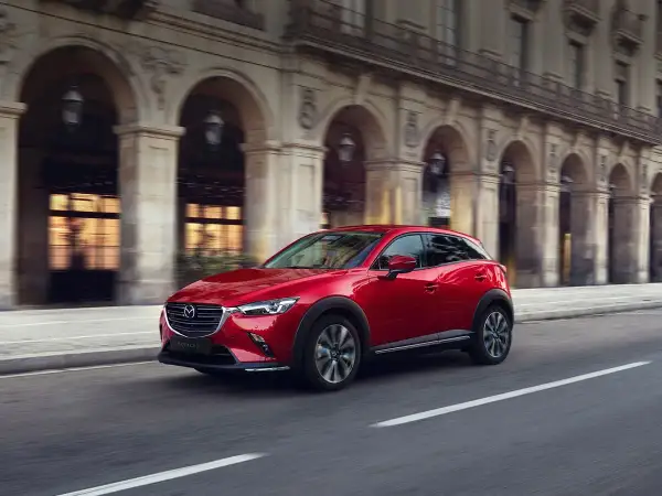 Czerwona Mazda CX-3 w ruchu miejskim. Wiele osób szuka mazda cx-3 opinie, by poznać ten stylowy crossover.